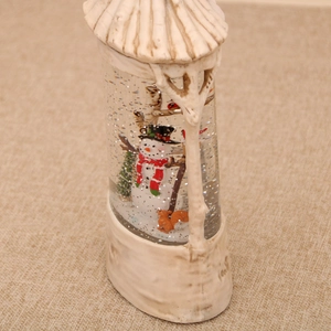 Detailed view of Christmas snow globe with snowman and squirrel in faux wood base