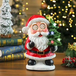 Detail of Santa resin figurine with glowing LED eyes and a lighted Christmas tree