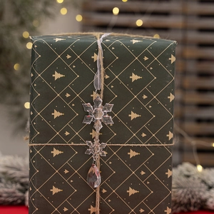 Detalle de copos de nieve de acrílico en caja de regalo verde con luces navideñas cálidas