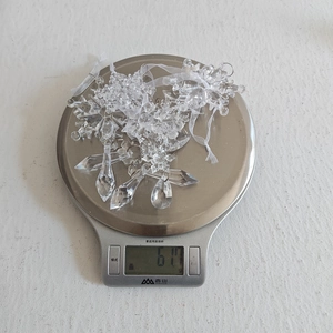 Medición del peso de los adornos de copos de nieve de acrílico transparente en báscula digital