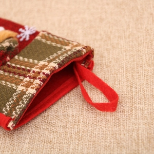 Close-up of red and green plaid Christmas stocking with white snowflake detail