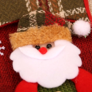 Detail of Santa Claus fabric ornament with felt beard and festive plaid hat textures