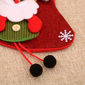 Detail of red burlap Christmas stocking featuring a 3D Santa doll with wooden button