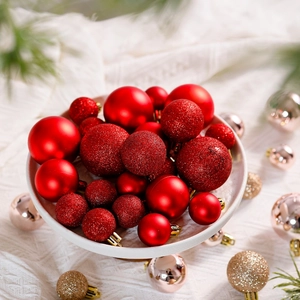 Detail of red Christmas ornaments set including matte and glitter finishes on white fabric