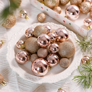 Detail of rose gold and gold Christmas ball ornaments in various sizes on a white tray