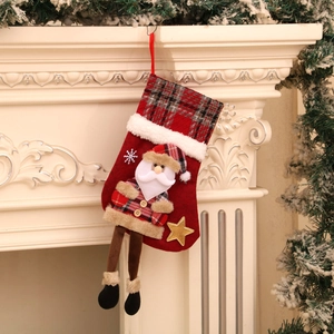 Detail of red Santa Claus plaid stocking hanging on a white fireplace mantel
