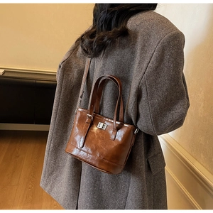 Vue latérale d'un sac cabas en cuir marron vintage porté avec un blazer gris pour le travail