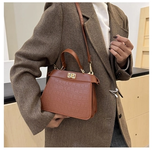 Detalle de bolso marrón con textura de cocodrilo y elegante cierre de giro metálico