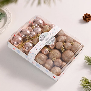 Macro shot of rose gold and glittery gold Christmas ornaments in a gift box with pine cones