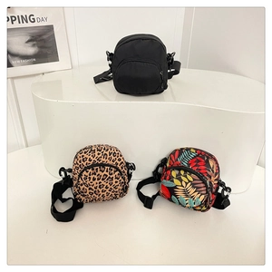 Detailed view of mini floral, leopard, and tropical print crossbody bags on a display stand
