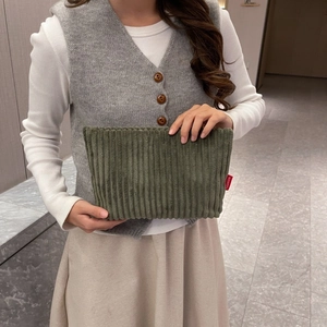 Détail de la pochette en velours côtelé vert avec étiquette rouge et texture rayée