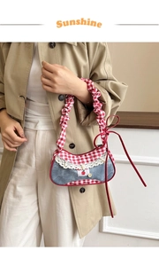 Detail of red and white checkered shoulder bag with cherry embroidery and lace trim