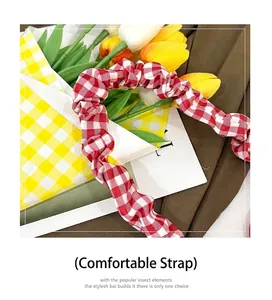 Close-up of a red and white gingham ruffled denim bag strap with floral accents