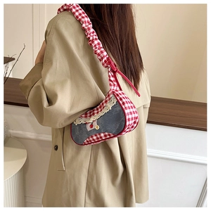 Detail of red gingham underarm bag with lace trim and cherry embroidery on shoulder