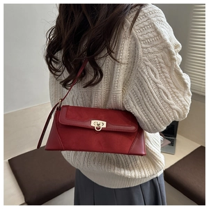 Close-up of deep red shoulder bag with gold ring buckle and mixed leather textures