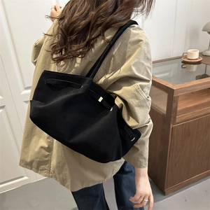 Minimalist black suede tote bag with metal buckles shown on a model for daily commute