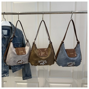 Close-up of retro shoulder bags in canvas and leather with Amite cartoon embroidery