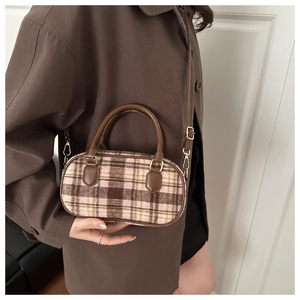 Detail der Vintage-Plaid-Muscheltasche mit braunem Lederbesatz auf braunem Mantel