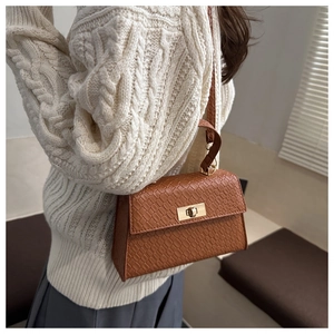 Detail of crocodile pattern texture on brown leather handbag with gold twist lock