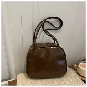Detail of vintage brown patent leather handbag with double straps on white knit blanket