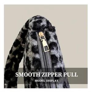 Detailed close-up of the smooth gold-toned metal zipper on a plush leopard print handbag