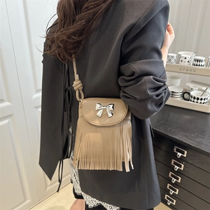Sac seau kaki à franges chic avec nœud en métal argenté porté par un mannequin chez soi