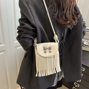 Sac seau blanc chic à franges avec boucle nœud argentée porté par un mannequin sur un blazer