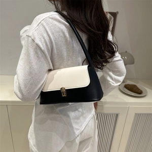 Chic black and white leather shoulder bag with gold metal lock on a model shoulder