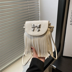 Détail du fermoir papillon argenté et des franges sur un sac seau couleur crème