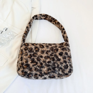 Detail of soft leopard print plush shoulder bag on minimalist white fabric background