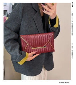 Vue détaillée de la texture tissée bordeaux sur pochette enveloppe avec fermoir doré