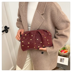 Detail of burgundy ruched clutch bag with gold studs and leopard print texture