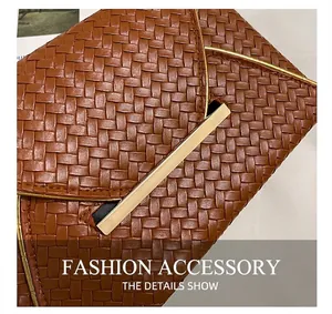 Détail de la texture tressée d'une pochette marron avec une barre en métal doré chic