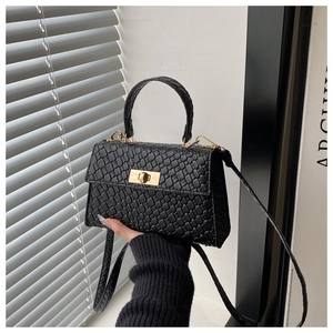 Close-up of black textured leather bag with gold twist lock and woven square pattern