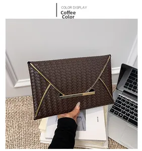 Détail de la pochette enveloppe tressée marron café avec bordure en métal doré en V