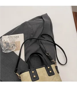 Detail of canvas bucket bag with leather handles, gold studs and adjustable shoulder strap