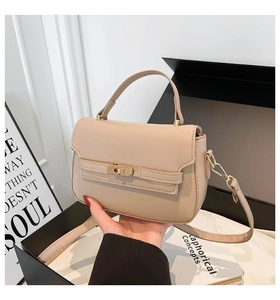 Macro detail of beige PU leather handbag showing the gold turn-lock closure and handle