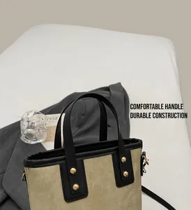 Close-up of canvas bucket bag with black leather handles and gold rivet details