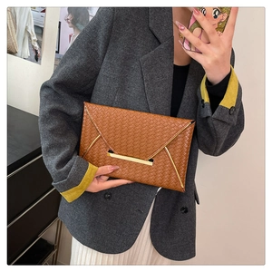 Gros plan d'une pochette enveloppe en cuir tressé marron avec bordure dorée chic