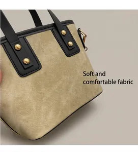 Close-up of canvas bucket bag featuring black leather trim and golden metal rivet details