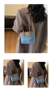 Close-up of blue denim bucket bag with brown leather trim and fashion lettering details