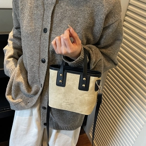 Mini sac seau beige et noir avec rivets dorés porté en bandoulière élégante