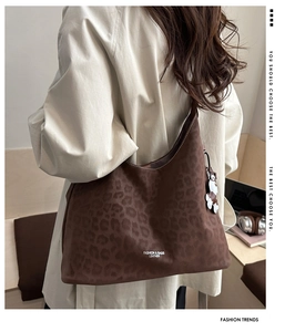 Detail of leopard print tote bag featuring a white flower charm and embossed brand text