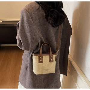 Détail de couture contrastée et bandoulière en cuir sur ce sac seau beige rétro pour femme