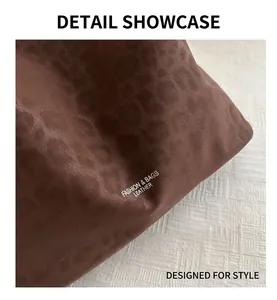 Detail shot of dark brown faux suede tote featuring embossed leopard pattern and white text