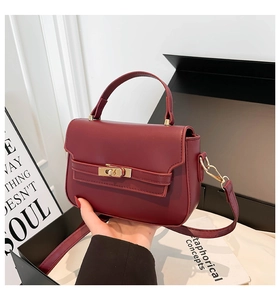 Macro view of burgundy leather handbag with golden twist lock and adjustable strap