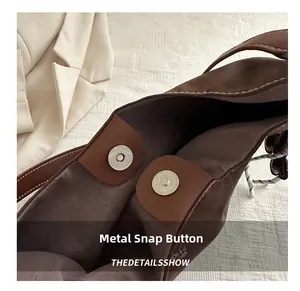 Detailed macro view of the brown suede tote bag featuring a dual magnetic snap closure