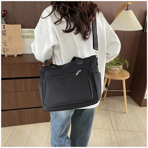 Detailed view of black nylon tote bag on model showing large size and storage pockets