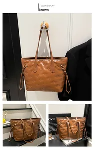 Detailed view of brown tote bag with embossed bow patterns and drawstring accents