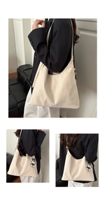Detail of cream faux leather tote bag with fashion text and bear charm accessory